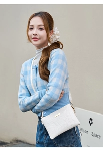Detailed view of white crocodile pattern shoulder bag with a gold buckle and adjustable strap
