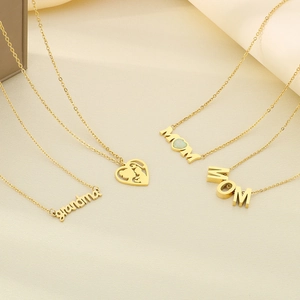 Detailed view of gold stainless steel MOM and grandma pendants on beige fabric
