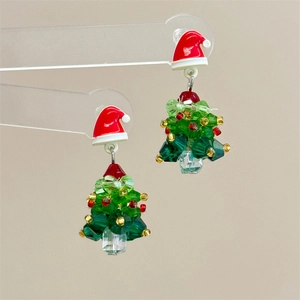 Macro view of beaded Christmas tree earrings with red hat details and colorful crystals