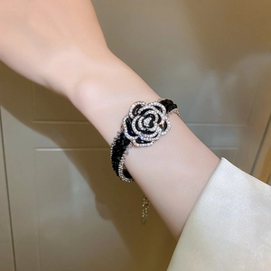 Detailed view of silver bracelet featuring black camellia and crystal beads on a wrist