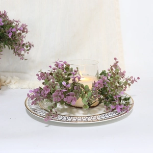 Close-up of purple eucalyptus candle ring wreath around glass jar on a white plate
