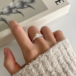 Detailed view of an S925 silver pearl ring worn on hand with elegant white knit background