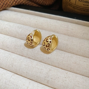 Vue détaillée des boucles d'oreilles dorées en forme de C avec motif léopard en émail