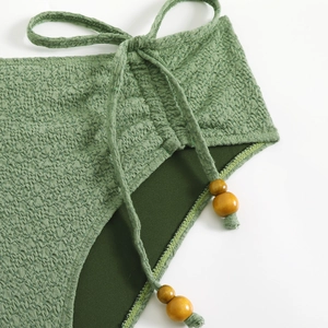 Detail of green seersucker bikini bottom featuring side ties and wooden bead accents