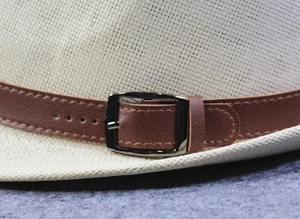 Detailed macro view of woven straw texture and brown leather strap with metal buckle
