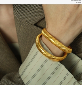 Detail of 10mm golden snake-bone textured spring bracelet on a model's wrist