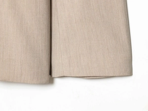 Detailed close-up of beige woven suit fabric texture and precise stitching on cuffs