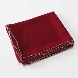 Detailed view of red silk-like scarf with golden bead chain trim on white background