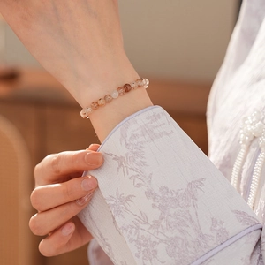 Detail of natural red rutilated quartz beaded bracelet on a woman's wrist