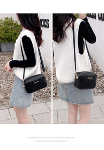 Close-up of black quilted camera bag with gold zipper and adjustable crossbody strap