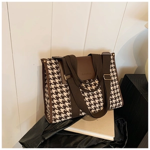 Close-up of houndstock tote bag with brown leather flap and wide fabric shoulder strap