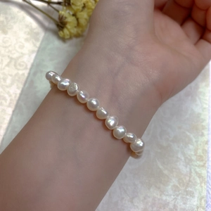 Close-up of irregular Baroque pearls on a 14K gold-filled bracelet worn on a wrist