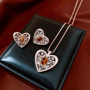 Detail of vintage filigree heart necklace and earrings set with oval brown gemstones
