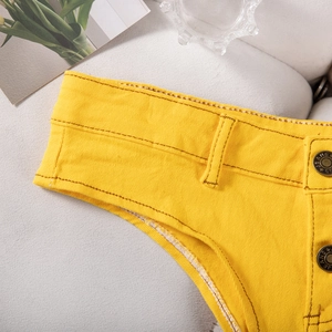 Détail macro du short en jean jaune avec bouton métallique et coutures marron