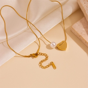 Golden heart pearl snake chain necklace with BEAUTY engraving on silk background
