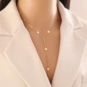 Long Y-shaped gold stainless steel necklace featuring heart and bar charms on a model