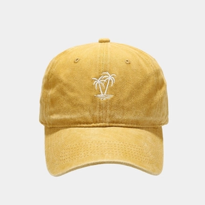Detailed view of white palm tree embroidery on a vintage washed yellow baseball cap