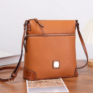 Close-up of brown pebbled leather texture and golden zipper on crossbody bag