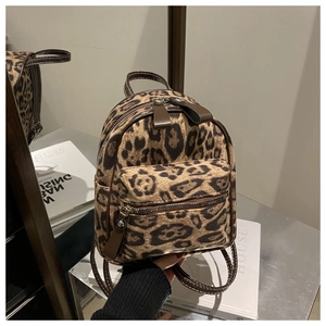 Detail view of leopard print mini backpack with brown trim and dual metal zippers