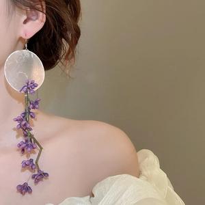 Detail of elegant asymmetric floral earrings with purple flower tassels and silver hooks