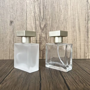 Detail of square glass perfume spray bottles in frosted and clear finishes with gold caps