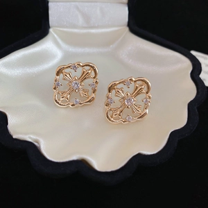 Macro shot of gold-plated hollow cross earrings with zircon in shell jewelry box