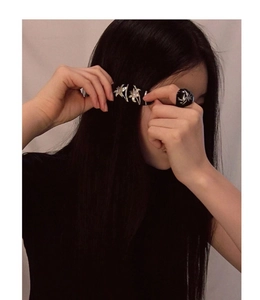 Close-up of elegant black hair clip and matching ring with silver floral pattern on a model