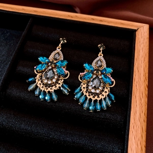 Detailed close-up of vintage bohemian crystal tassel earrings in a wooden jewelry box