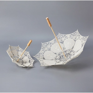 Detailed embroidery texture on white lace wedding umbrella with classic wooden handle