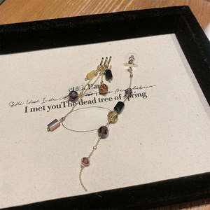 Macro detail of long tassel earrings with amber and black crystal beads in a gift box