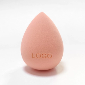 Detailed close-up of a teardrop-shaped makeup sponge in peach pink with logo imprint