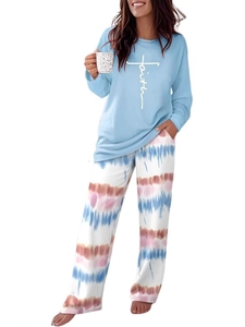 Detail of knitted pajama set featuring blue 'faith' print top and tie-dye striped pants