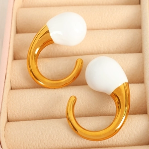 Chic golden C-shaped hoop earrings with large white enamel charms in a jewelry box