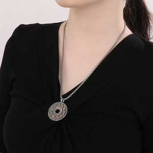 Detailed close-up of a vintage-style two-tone circular pendant on a long silver chain