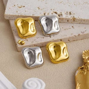 Artistic detail of irregular geometric 18k gold and silver earrings on textured stone