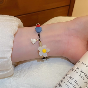 Détail d'un bracelet perlé fait main avec fleurs blanches et cœurs bleus porté au poignet