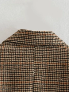 Détail du revers d'un blazer à carreaux pied-de-poule montrant la texture de la laine
