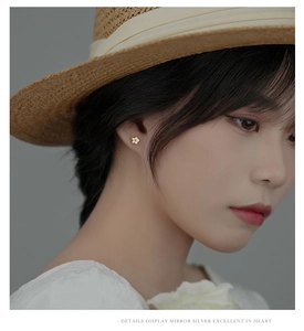 Detail showing a woman wearing small golden flower sterling silver screw back earrings