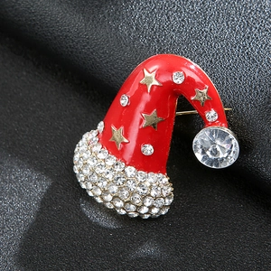Macro view of Christmas hat brooch with red enamel, gold stars and white rhinestones
