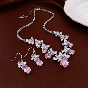Detailed view of pink teardrop zircon necklace and earrings set on dark leather