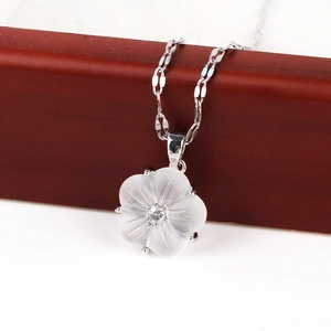 Close-up of flower pendant in white shell finish with crystal center and silver chain