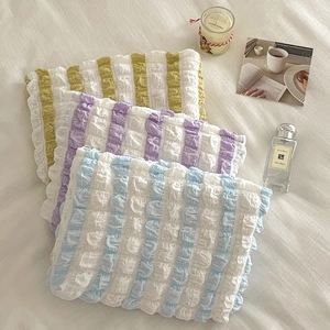Detail view of colorful striped ruffled fabric texture on portable makeup bags