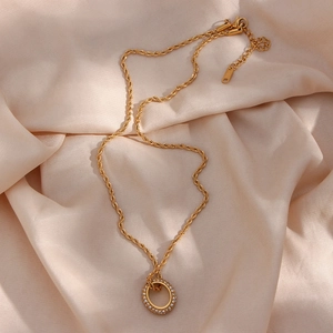 Close-up of gold double-ring pendant with zircon stones on silk fabric background