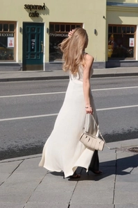 Close-up of cream sleeveless knit maxi dress with elegant flowing hem and textured fabric