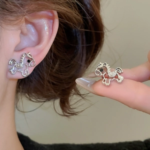 Close-up of model wearing silver hollow horse stud earring with black eye detail