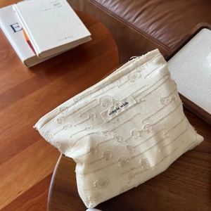 Beige textured cotton linen makeup bag with Simple Wish label on vintage wooden table