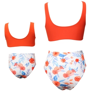 Detail view of two-piece swimwear with orange crop top and floral high-waist bikini bottoms