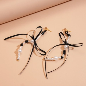 Détail de boucles d'oreilles nœuds en soie noire avec élégants pompons de perles