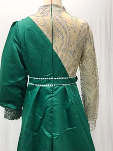 Detail of green satin evening dress featuring silver sequin mesh sleeve and belt detail
