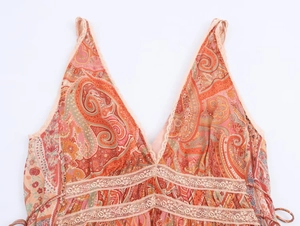 Dettaglio del motivo paisley boho con pizzo beige e scollo a V del vestito estivo